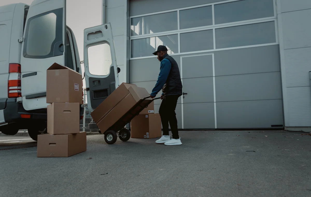HBS Logistikpersonal transportiert Kartons zu einem Lieferwagen